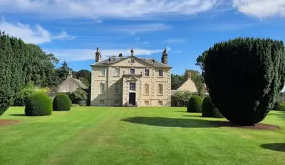 a large house on a green lawn with bushes at Newton Mearns Home in Newton Mearns