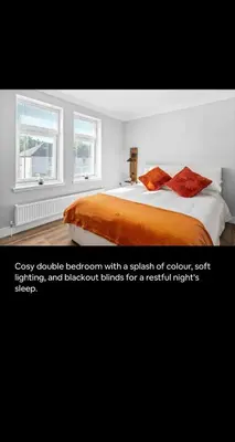 a bedroom with a bed with orange sheets and two windows at 2BR bed home peaceful central area free parking in Oban