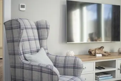 a living room with a plaid chair and a television at The Steading In The Park in Stirling