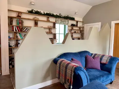 a living room with a blue couch and bookshelves at The Steading In The Park in Stirling