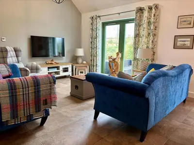 a living room with a blue couch and a tv at The Steading In The Park in Stirling