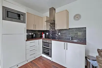 a kitchen with white cabinets and a sink and a microwave at Turbine House in Lochgilphead