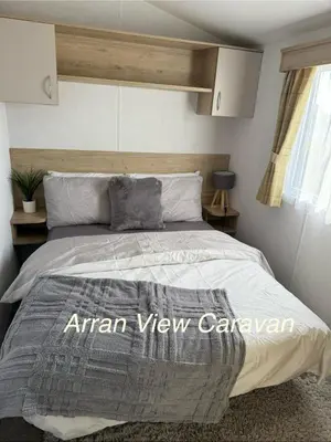 a bedroom with a bed with a gray comforter at Arran View Caravan in Ayr