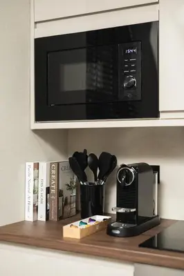 a kitchen counter with a microwave and a shelf with utensils at South Lane Apartments - City Centre in Edinburgh