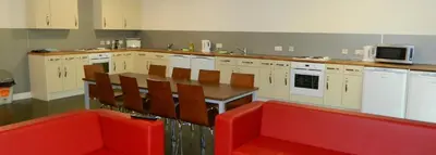 a kitchen with a wooden table and red chairs at Alexander Court Townhouse in Stirling