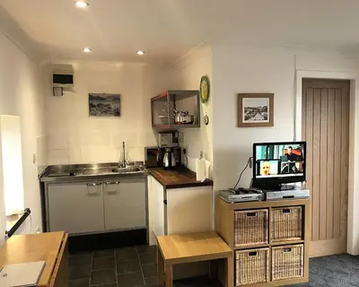 a kitchen with a sink and a counter with a television at Pier Cottage at Kames in Kames
