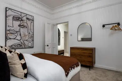 a bedroom with a large bed and a mirror at Stirling Edwardian House - Fireplace,Garden,Parking in Stirling