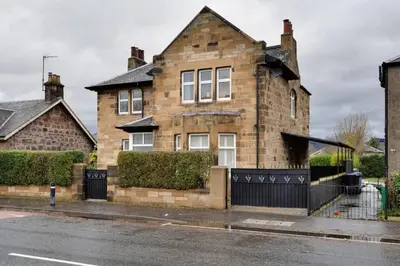 a brick house with a black fence in front of it at Stirling Edwardian House - Fireplace,Garden,Parking in Stirling