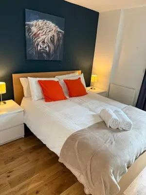 a bedroom with a large white bed with red pillows at Stylish Clyde Riverfront Flat with Balcony Views in Glasgow