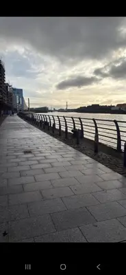 a sidewalk next to a body of water with a fence at Stylish Clyde Riverfront Flat with Balcony Views in Glasgow