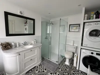 a bathroom with a shower sink and a washing machine at Mid- Village Croft in Cairndow