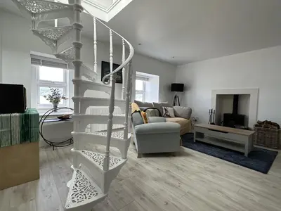 a living room with a spiral staircase in a house at Mid- Village Croft in Cairndow