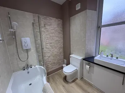a bathroom with a toilet and a shower and a sink at Station Road Apartment - Macaulay Letting in Dumbarton