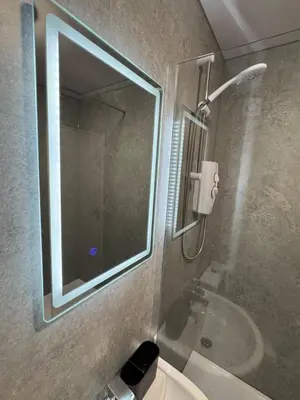 a bathroom with a shower and a sink and a mirror at Central 1BR Apt with Parking in Auchterarder