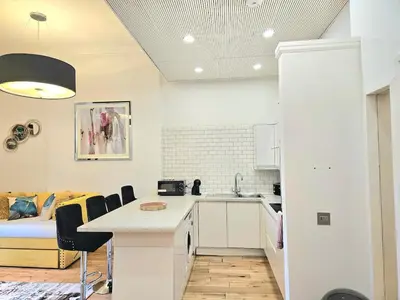 a white kitchen with a table and a bed at Stellar Apartments - 2 & 3 Bedroom Apartments in Edinburgh