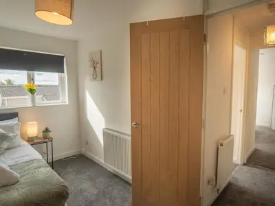 a bedroom with a wooden door and a bed at Etive House - 3 bedroom stylish home in Cumbernauld