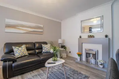 a living room with a leather couch and a fireplace at Culzean House - 2 Bedrooms in Coatbridge in Coatbridge