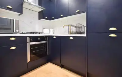 a kitchen with navy blue cabinets and a microwave at Portside Apartment in Greenock