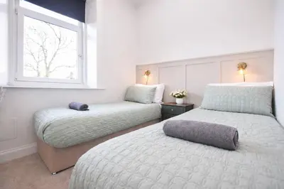 a bedroom with two beds and a window at Portside Apartment in Greenock