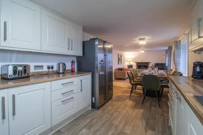 a kitchen with white cabinets and a table and a dining room at Lynwood - 4 Bedroom House with Views of Loch Gilp in Ardrishaig