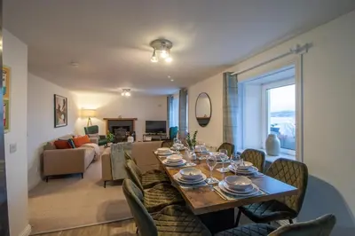a dining room with a table and chairs and a living room at Lynwood - 4 Bedroom House with Views of Loch Gilp in Ardrishaig