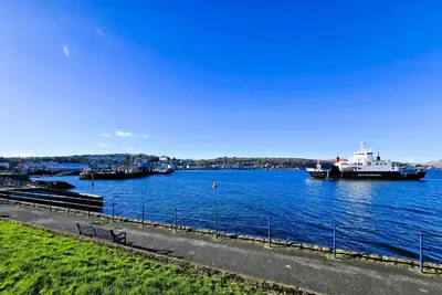 a bench next to a body of water with boats at Harbour View - Luxury Town Centre Property in Rothesay
