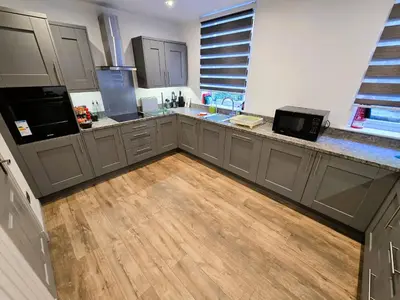 a kitchen with gray cabinets and a wooden floor at Harbour View - Luxury Town Centre Property in Rothesay