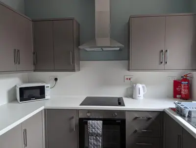 a kitchen with white cabinets and a stove top oven at Argyll Place in Campbeltown