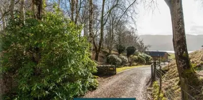 a dirt road with trees and a fence on it at Coach House at Morenish Mews in Killin