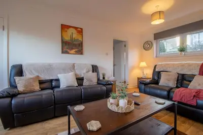 a living room with a leather couch and a table at Raeburn House- 3 Bedrooms, 2 Bathrooms in Hamilton in High Blantyre