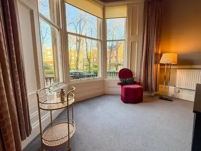 a room with a large window with a chair and a table at Spacious Three Storey West End Home - 3 bedroom in Glasgow