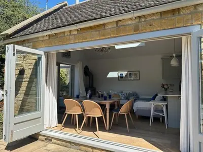 a patio with a table and chairs and a kitchen at Charming Cotswold stone cottage with garden in Moffat