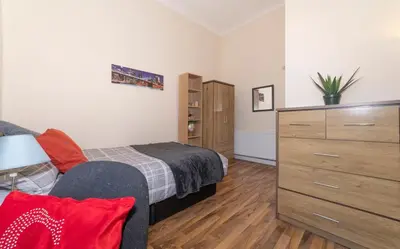 a small bedroom with a bed and a dresser at 7 Bedroom Apartment - City Centre in Glasgow