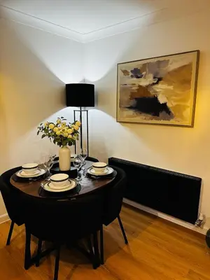 a dining room table with a vase of flowers on it at Modern 2 Bedroom Ground Floor Apartment near city centre in Glasgow