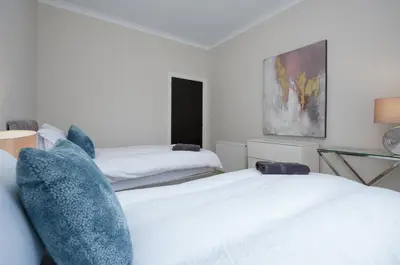 two beds in a white room with blue pillows at 3BR Home Sleeps 6 Near Airport with Parking