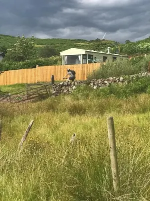 a person sitting on a fence in a field at Cruachan View Caravan Farm stay in Oban