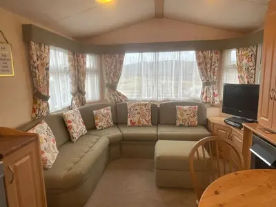 a living room with a couch and a tv at Cruachan View Caravan Farm stay in Oban