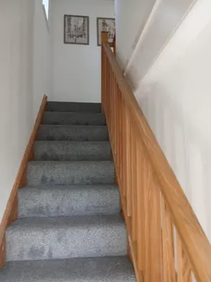 a staircase with wooden railings and gray carpet at Fabulous 4 Bed House in Leiston in Moffat