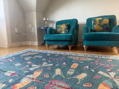 a living room with two blue chairs and a rug at Murrayfield Gem in Edinburgh
