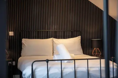 a bed with a black head board and white pillows at No8 Peebles Retreat - Donnini Apartments in Ayr