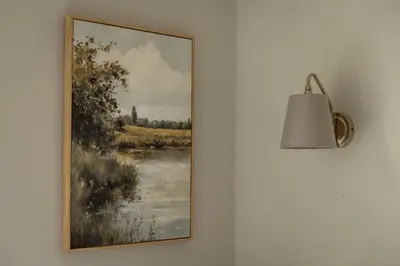 a painting of a river on a wall with a lamp at Cosy Callander One Bed Apartment Wood Burner and Free Parking in Callander