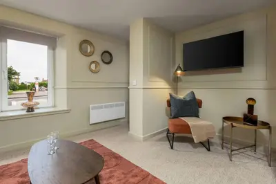 a living room with a tv and a chair and a table at The Bruces Quarter in Stirling