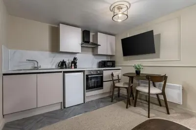 a kitchen with white cabinets and a table with chairs at Kilted Quarter by The Wallace Monument in Stirling