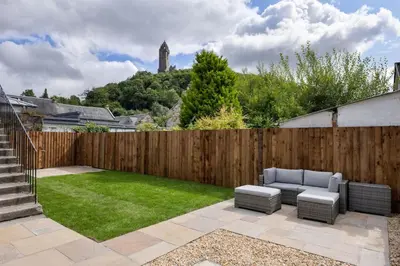 a backyard with a fence and a couch and grass at Kilted Quarter by The Wallace Monument in Stirling