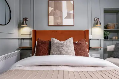 a bedroom with a bed with pillows and two lights at Caledonia Suite by The Wallace Monument in Stirling