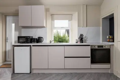 a white kitchen with white cabinets and a window at Caledonia Suite by The Wallace Monument in Stirling