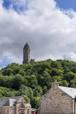 a castle on top of a hill with trees at The Wallace Suite by The Wallace Monument in Stirling