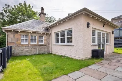 a small house with a grass yard in front of it at Kings Park Garden Cottage - Free Parking in Stirling