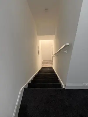 a staircase in a building with white walls and black carpet at West End Stay by Kelvingrove in Glasgow
