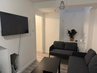 a living room with a couch and a tv on a wall at West End Stay by Kelvingrove in Glasgow